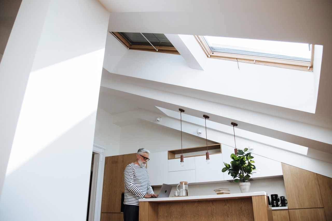 Senior adult working on a laptop in the kitchen, one option to make money from home