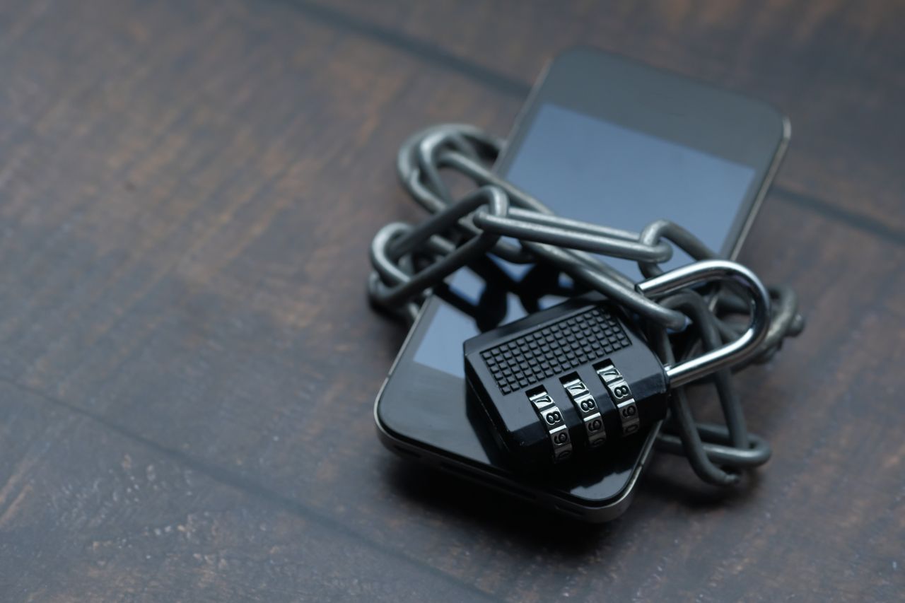 Smartphone wrapped in a chain and padlock, a reminder to secure your phone against risky downloader APKs