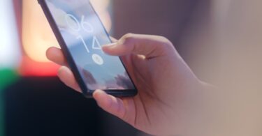 Hand holding a smartphone locked with a fingerprint sensor, protecting accounts from Instagram+ mod risks