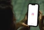 Hand holding a smartphone with the Instagram app open, home of the most followed personalities on Instagram