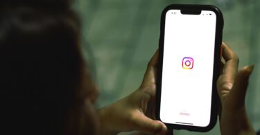 Hand holding a smartphone with the Instagram app open, home of the most followed personalities on Instagram
