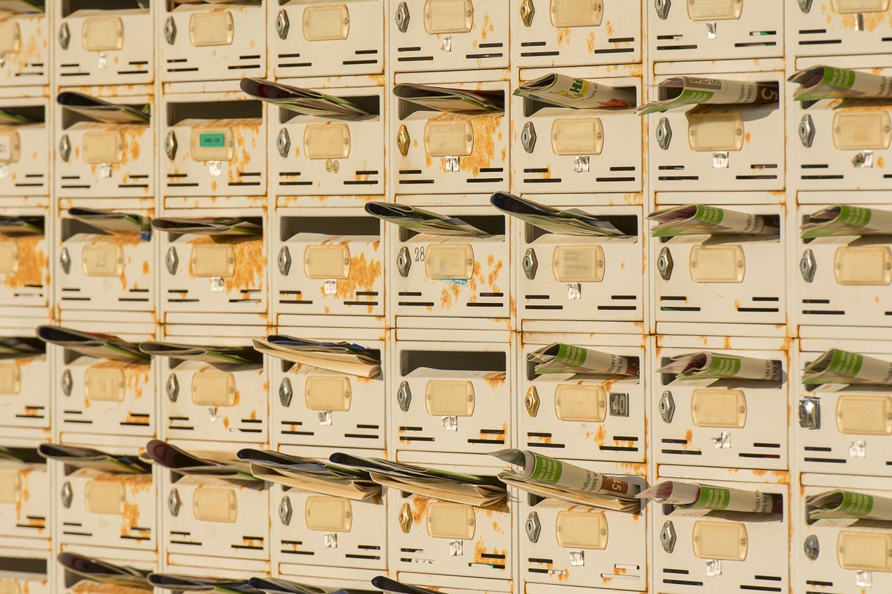 Row of metal mailboxes full of newsletters, a nod to choosing Sendloop alternatives for email