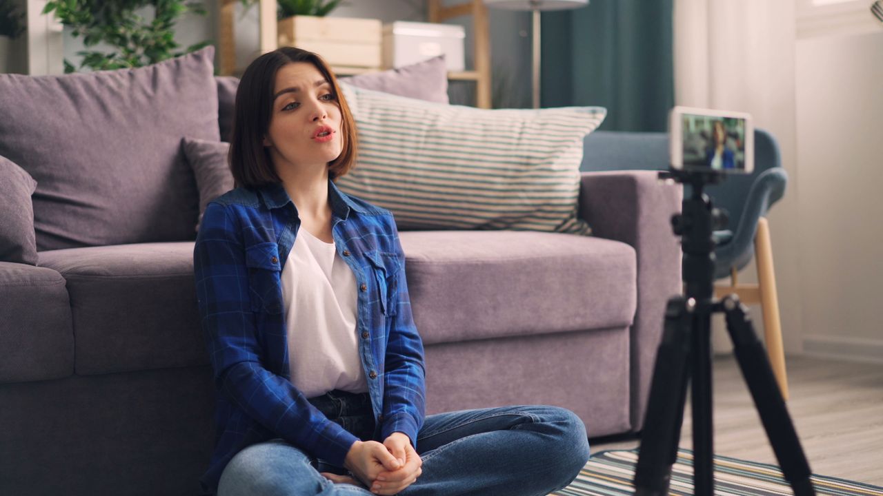 Creator sitting on the floor recording a video on her smartphone, content covered by Instagram video download rules