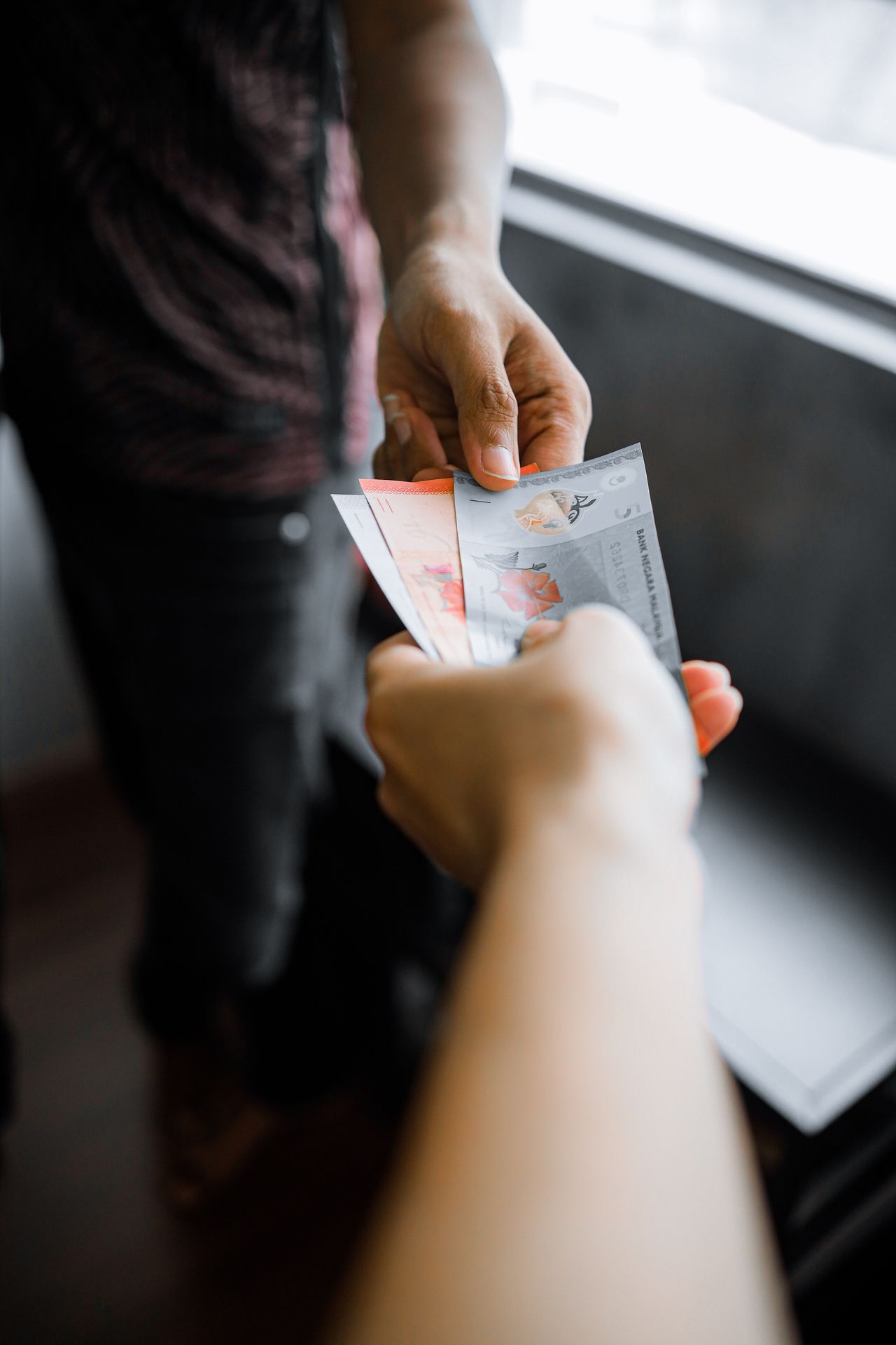Hands exchanging Malaysian ringgit notes, reflecting EasyStore pricing for sellers in Malaysia