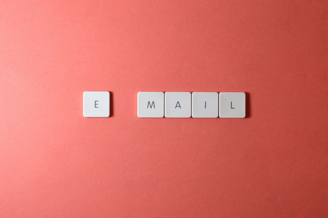 Letter tiles spelling the word email on a coral background, illustrating an AWeber email marketing review