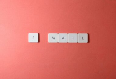 Keyboard letter tiles spelling email on a coral background, for a Benchmark Email review