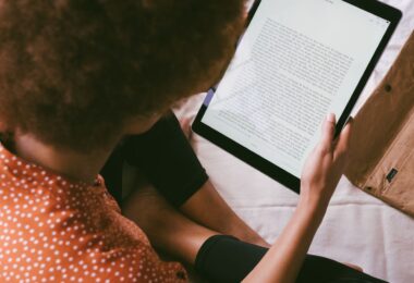 Woman reading an ebook on a tablet, the kind of digital download sold and delivered with SendOwl