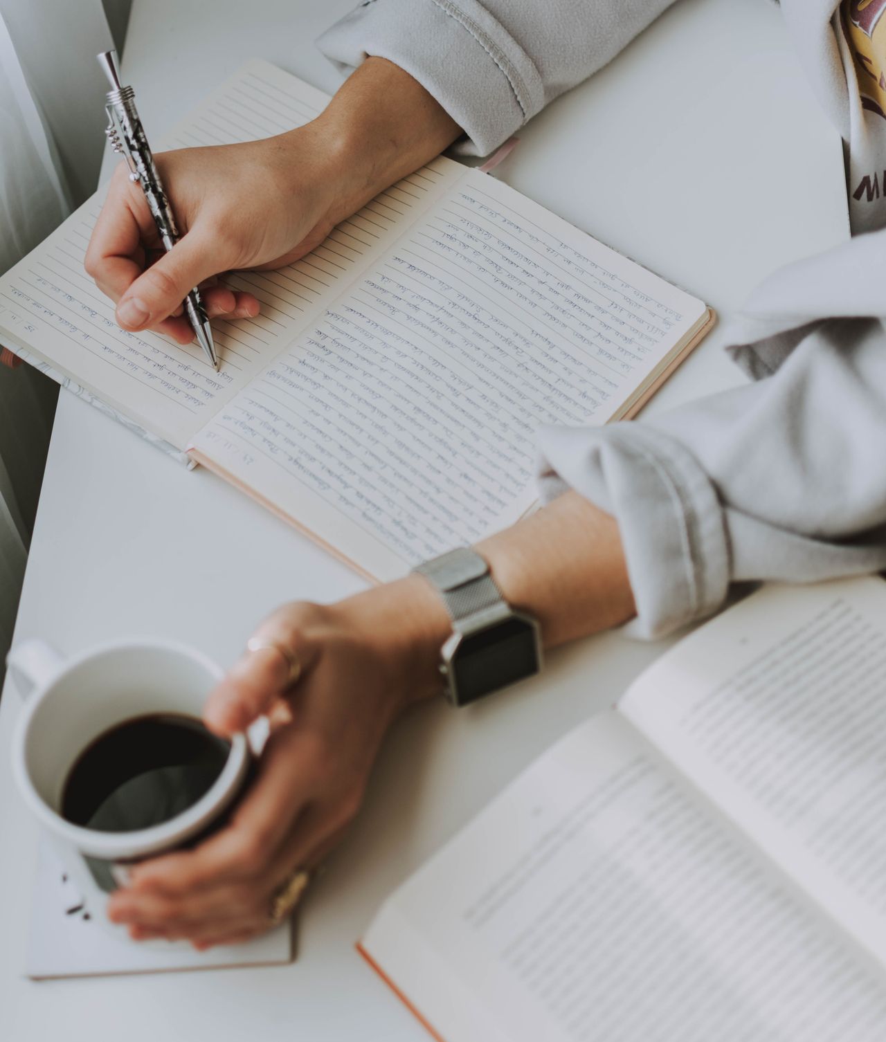 Person drafting ideas in a notebook with a coffee mug, planning how to make money writing online