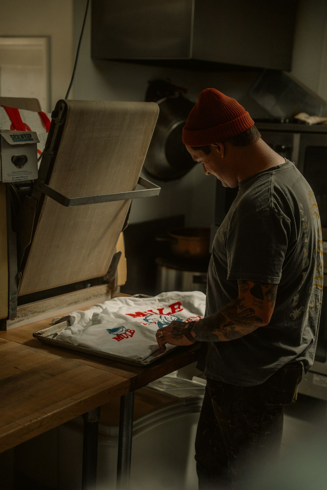 Man printing a custom T-shirt with a heat press, like the print-on-demand merch you can sell on Sellfy