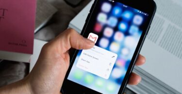Hand holding a smartphone with an email app open, representing AWeber free email marketing