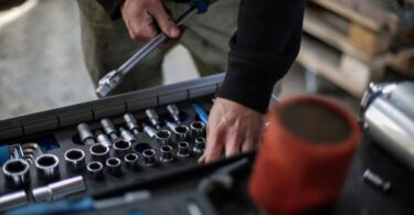 Mechanic choosing metal sockets in a workshop, for an X-Cart review of its auto parts ecommerce platform
