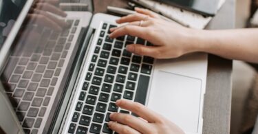 Woman using a laptop at her table, learning how to make extra money from home legitimately