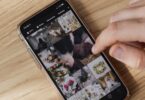 Person scrolling a smartphone photo gallery on a wooden table, saving pictures without an Instagram photo downloader