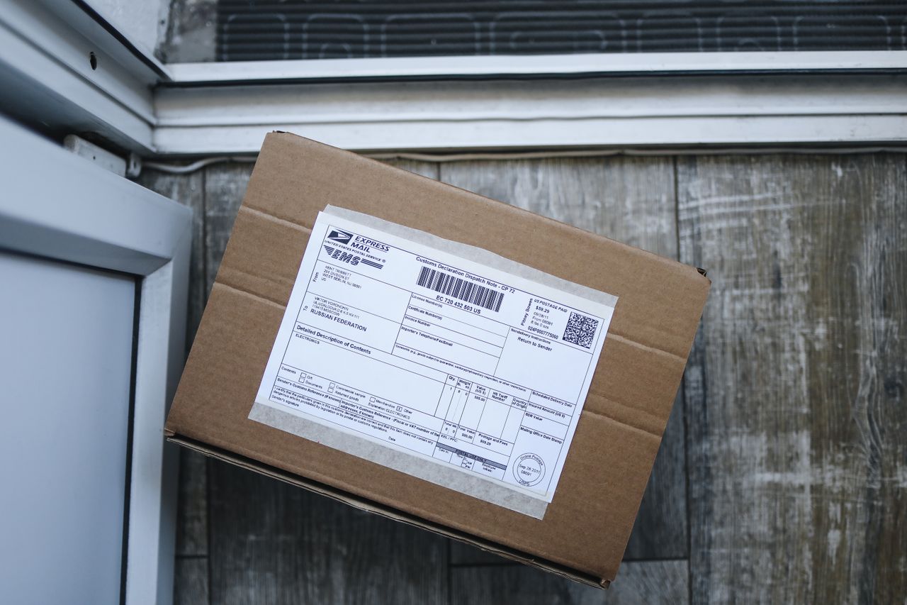 Cardboard box with a shipping label by a door, the details USPS asks for in a missing package search