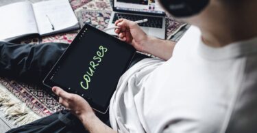 Person studying an online course on a tablet with headphones, for a Podia review of course selling