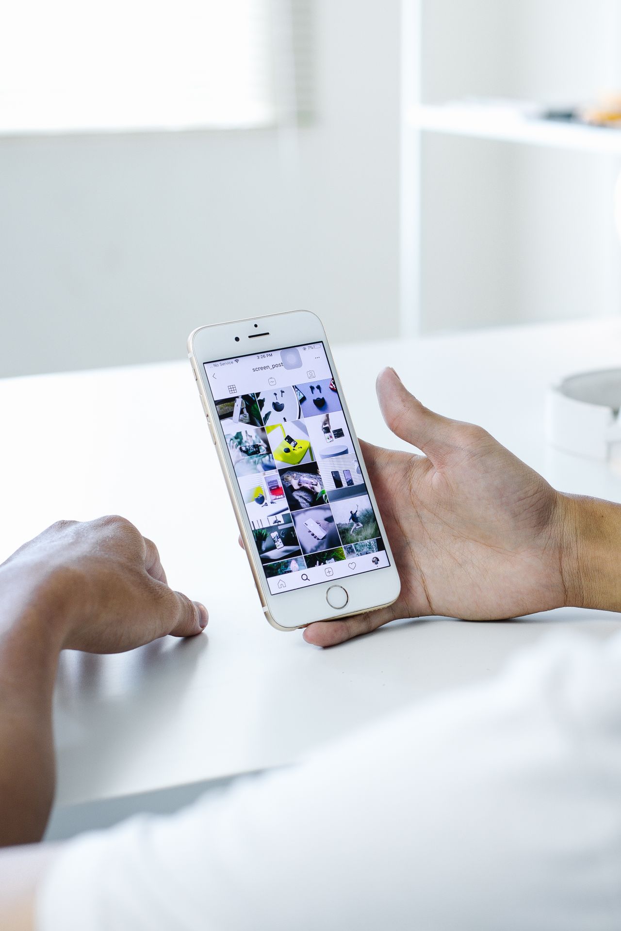 Hands holding a smartphone showing a gallery of saved images, an official Instagram photo download option