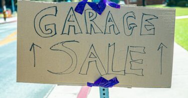 Garage sale sign on a post; selling items you own is how to make money in one hour