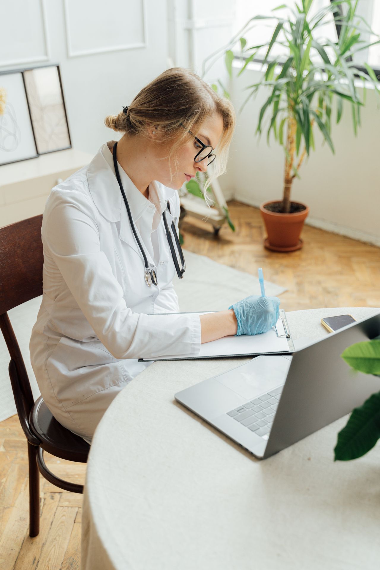 Doctor writing notes on a clipboard, the kind of records typed up in medical transcription work
