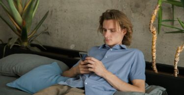 Man with a mobile phone on a sofa, trying apps to make easy money online