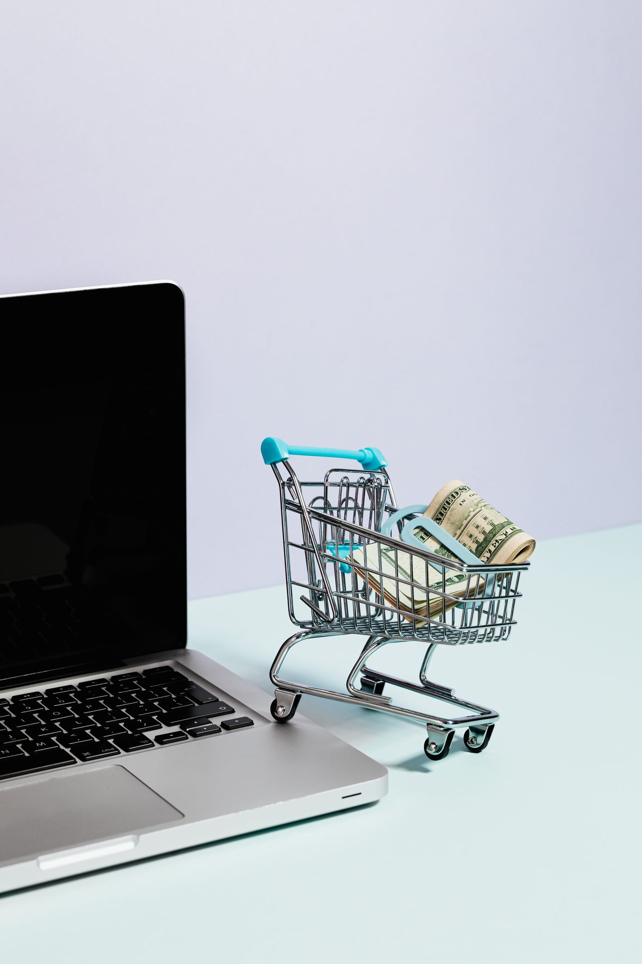 Shopping cart with cash on a laptop, showing the hidden costs of an ecommerce website builder