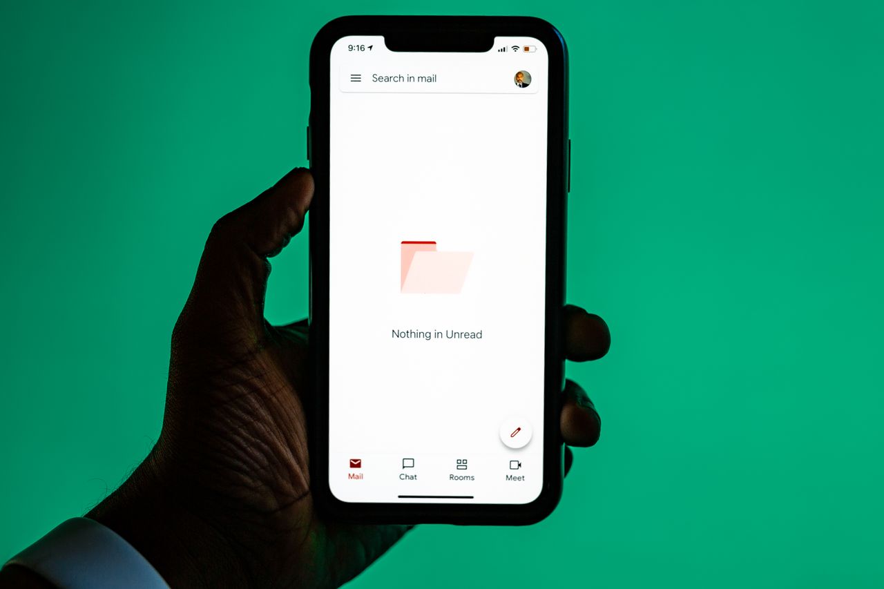 Hand holding a smartphone with an email app open, illustrating Sendlane pricing for email and SMS sends