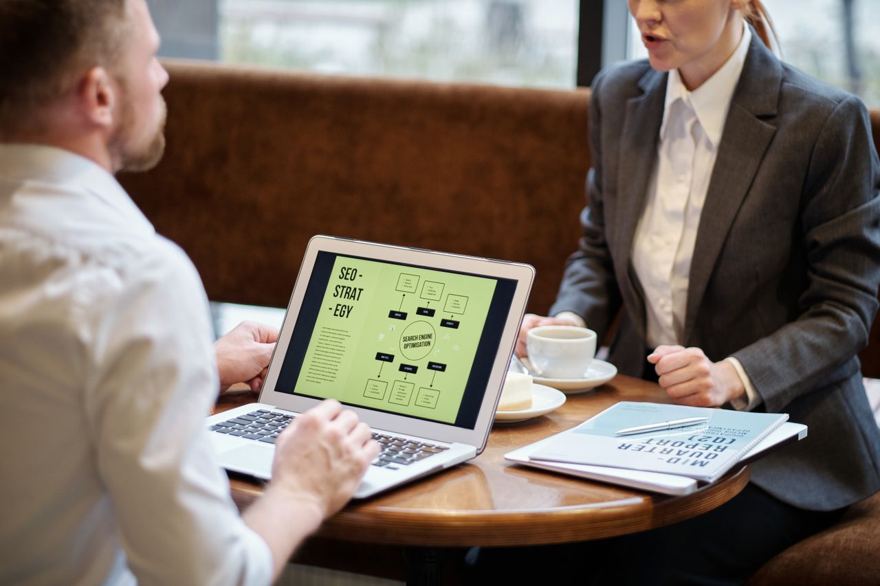 Man and woman discussing SEO and marketing tools in a cafe meeting