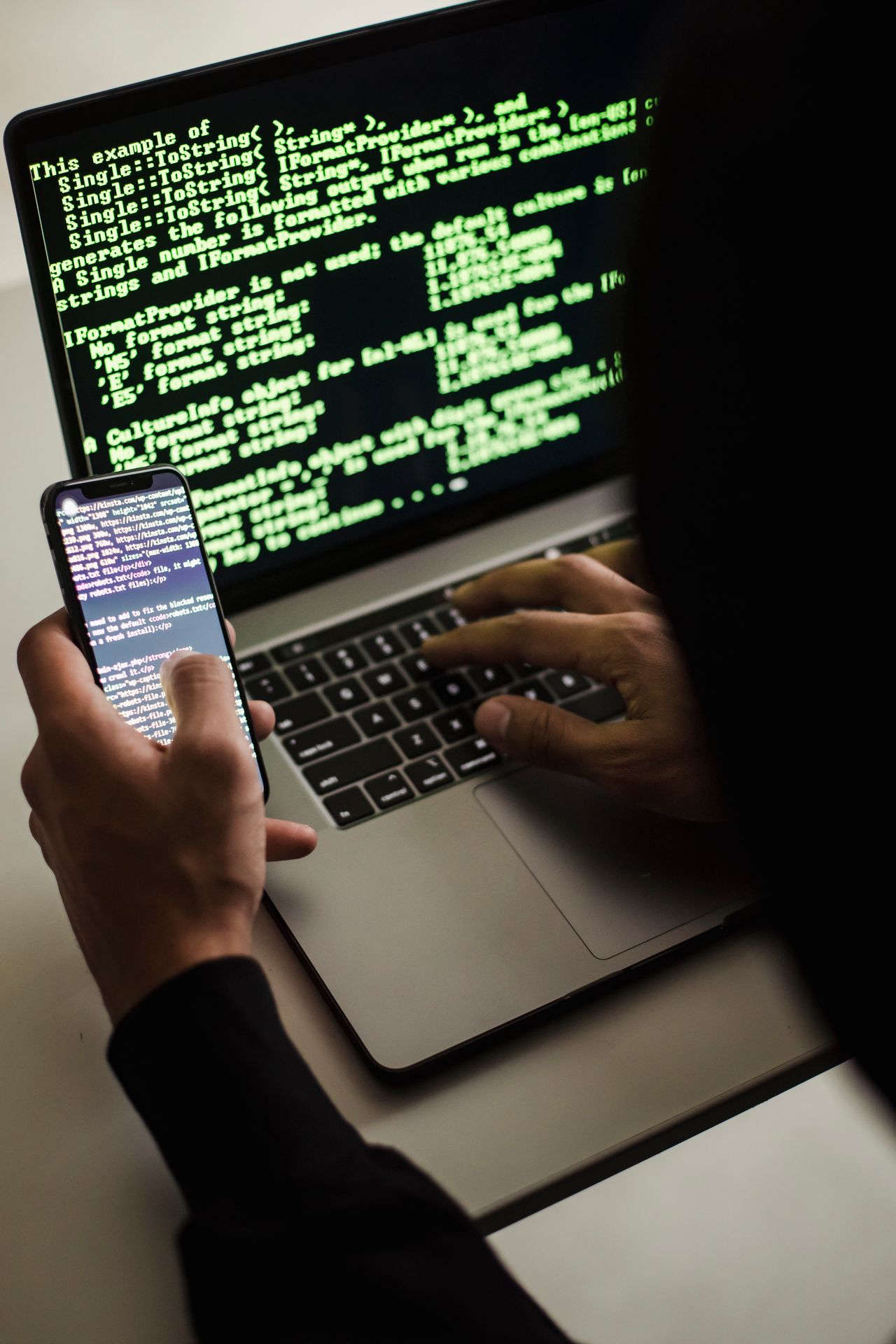 Anonymous hacker using a phone and laptop, showing how Instagram Plus mods can steal logins