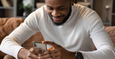 Man on a sofa using his smartphone to take online surveys for money