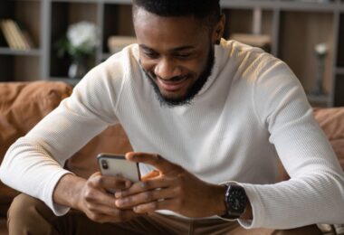 Man on a sofa using his smartphone to take online surveys for money
