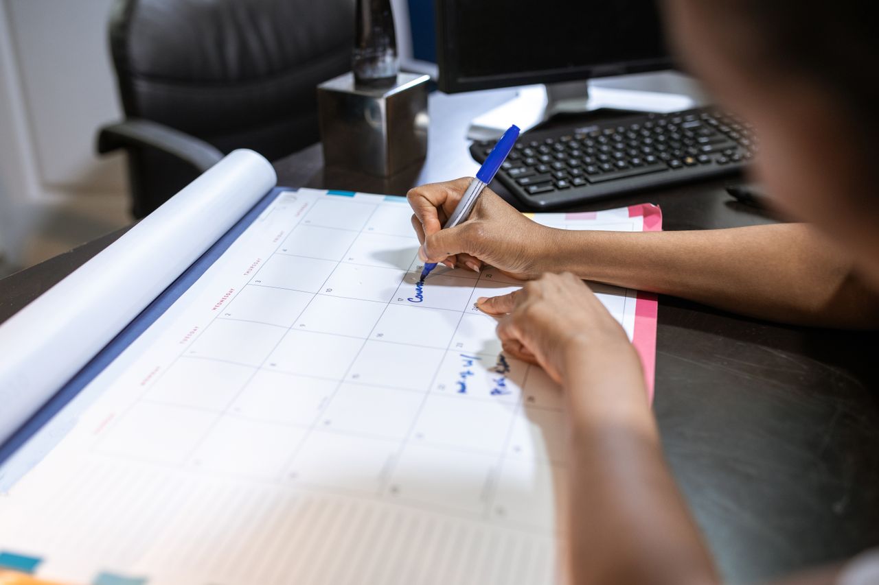 Person marking dates on a desk calendar to plan a Shopify free trial and the $1 months that follow