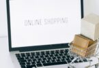 Miniature shopping cart and smartphone on a laptop, representing the best ecommerce website builder for online stores