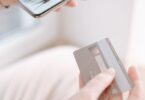 Hands holding a smartphone and credit card while shopping online, for a Sendlane review of ecommerce email and SMS
