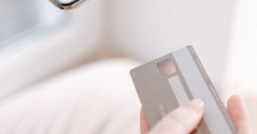 Hands holding a smartphone and credit card while shopping online, for a Sendlane review of ecommerce email and SMS