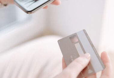 Hands holding a smartphone and credit card while shopping online, for a Sendlane review of ecommerce email and SMS