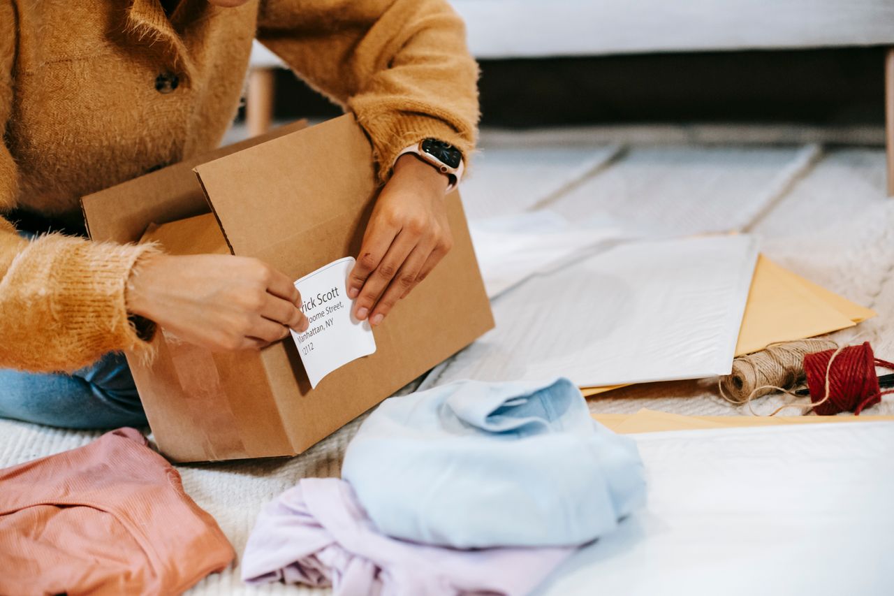 Seller sticking a shipping label on a parcel, one of the easy ways to make money online by reselling items