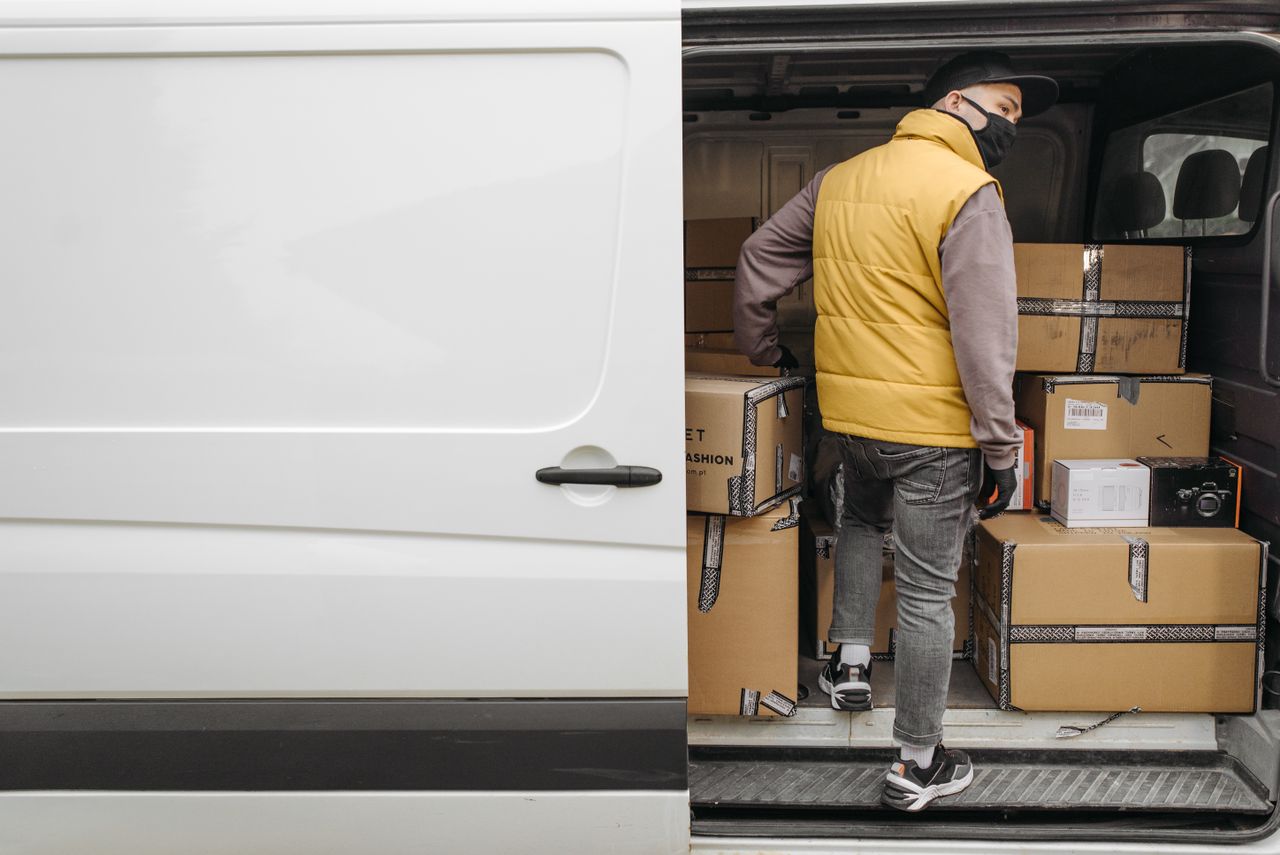 Delivery driver unloading packages from a van, the Out for Delivery stage in USPS tracking