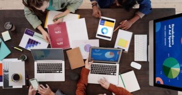 Team discussing digital marketing tools and strategy at a desk with laptops and tablets