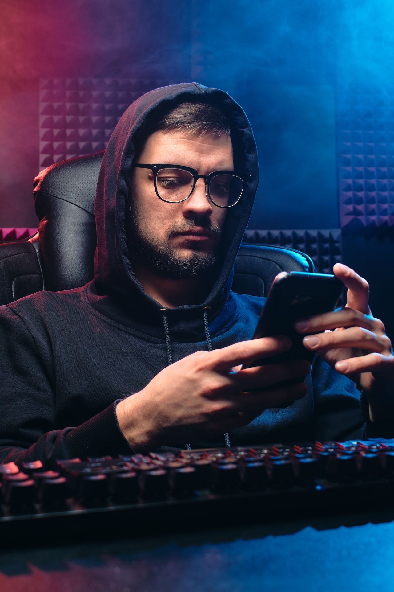 Man in a hoodie using a mobile phone, a reminder of the privacy risks of modded apps like Instagram+