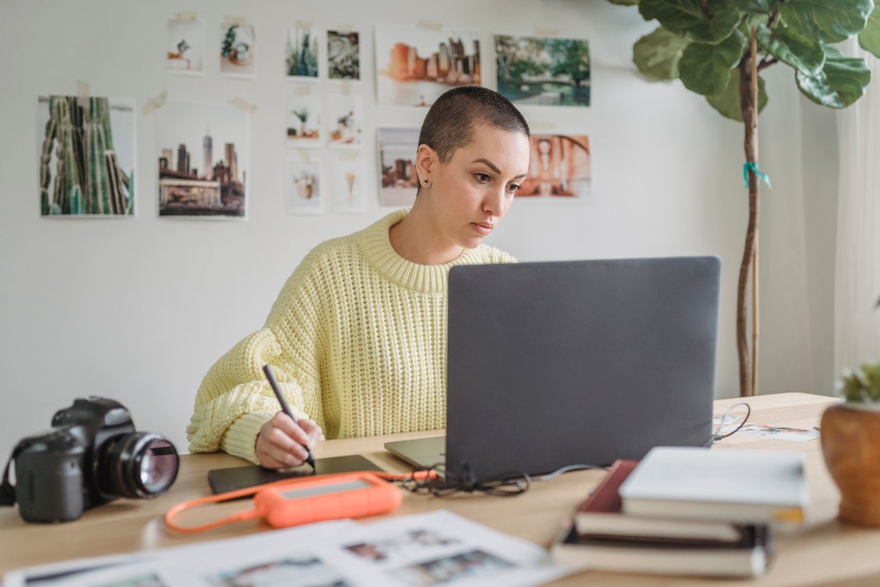Woman working on a laptop with a drawing tablet, earning from home with design skills