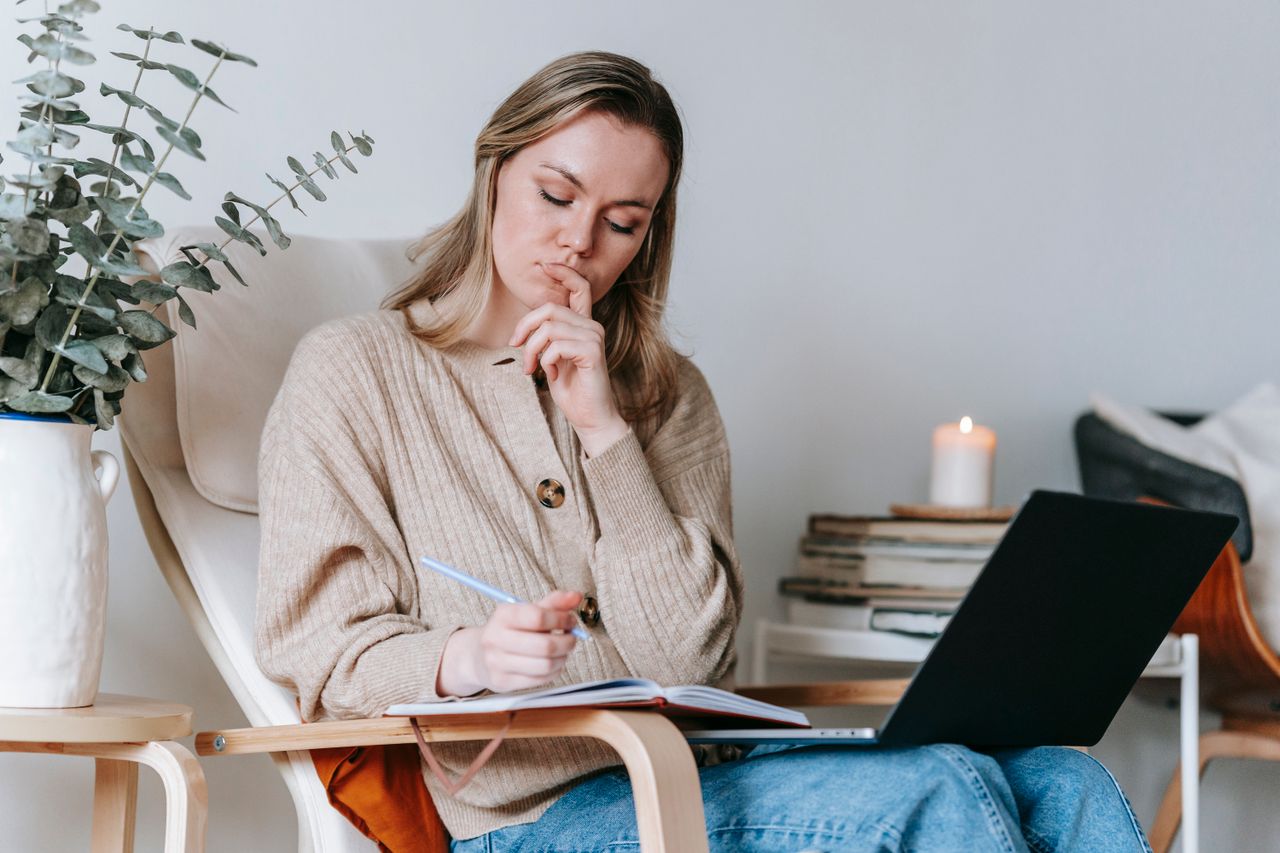 Beginner taking notes in a planner next to a laptop while learning how to make money online
