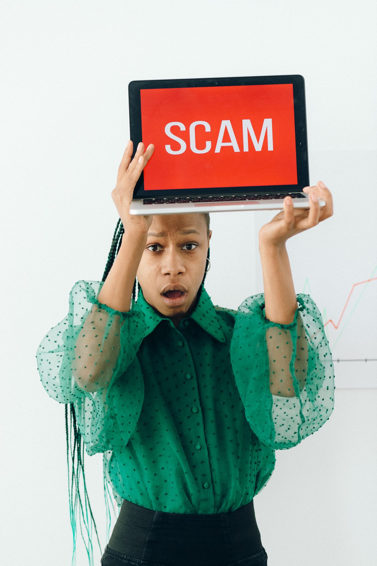 Woman holding a laptop that displays a scam alert, a warning sign when judging any Instadownloader site