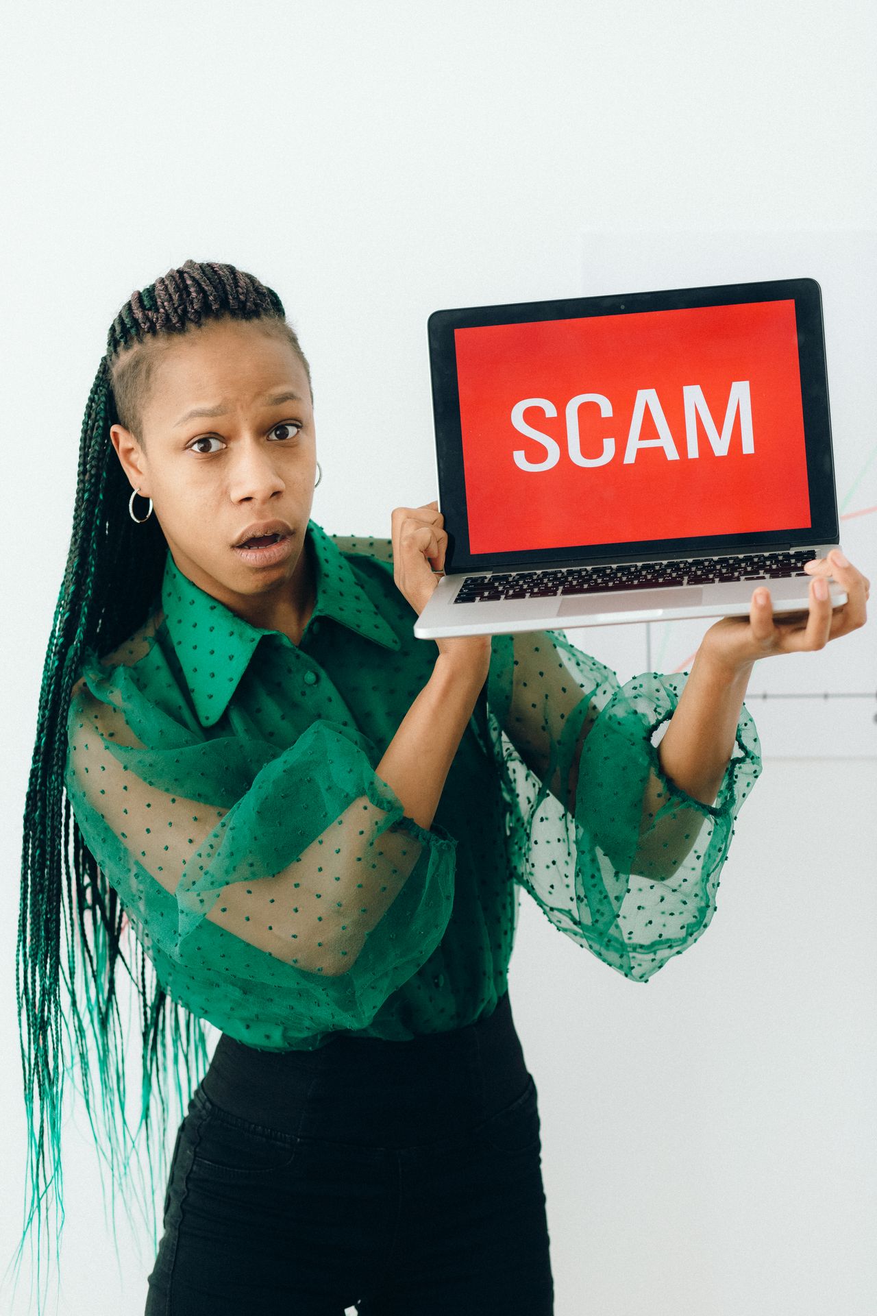 Shocked woman holding a laptop showing a scam alert, a common risk of online Instagram video downloader sites