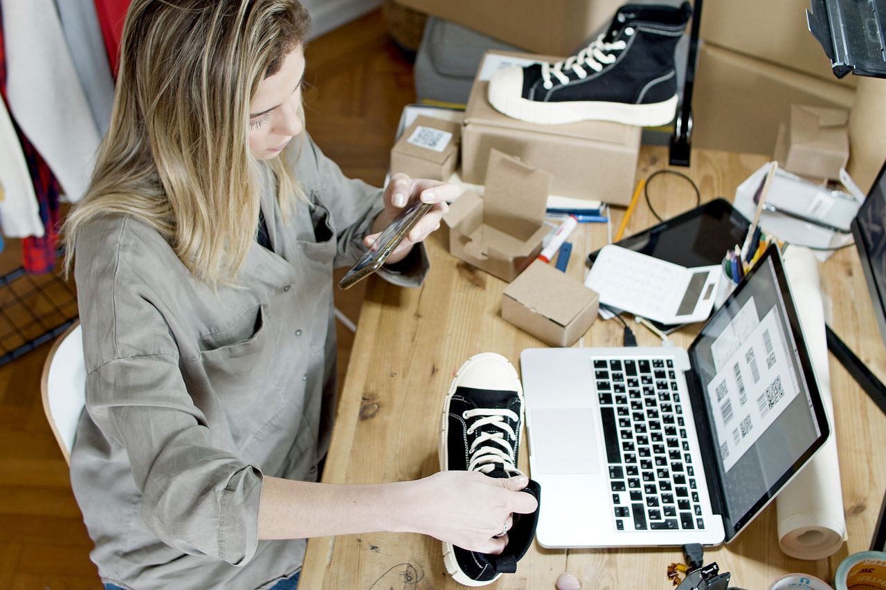 Woman photographing a product with her phone to prepare listings before starting a Shopify trial