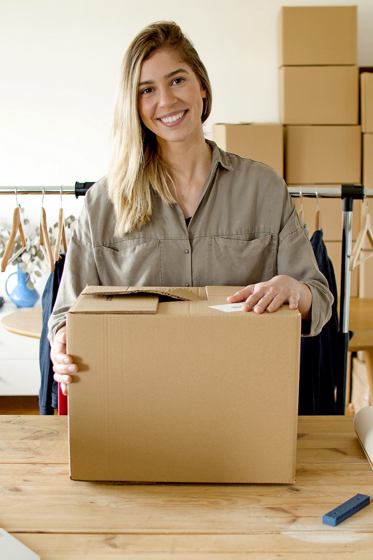 Smiling woman holding a package to ship after selling items, a free way to make money online