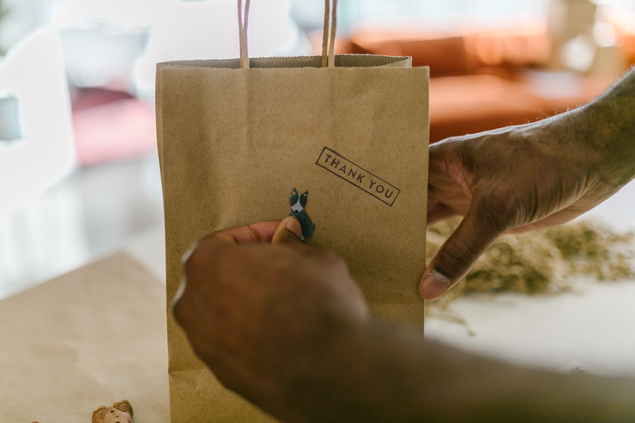 Hands holding a small business thank-you paper bag, for sellers checking whether Shopio is still active