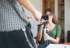 Young woman recording a vlog on a smartphone tripod, creating Reels people try to save with an Instagram video downloader
