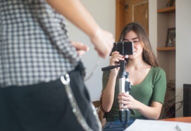 Young woman recording a vlog on a smartphone tripod, creating Reels people try to save with an Instagram video downloader