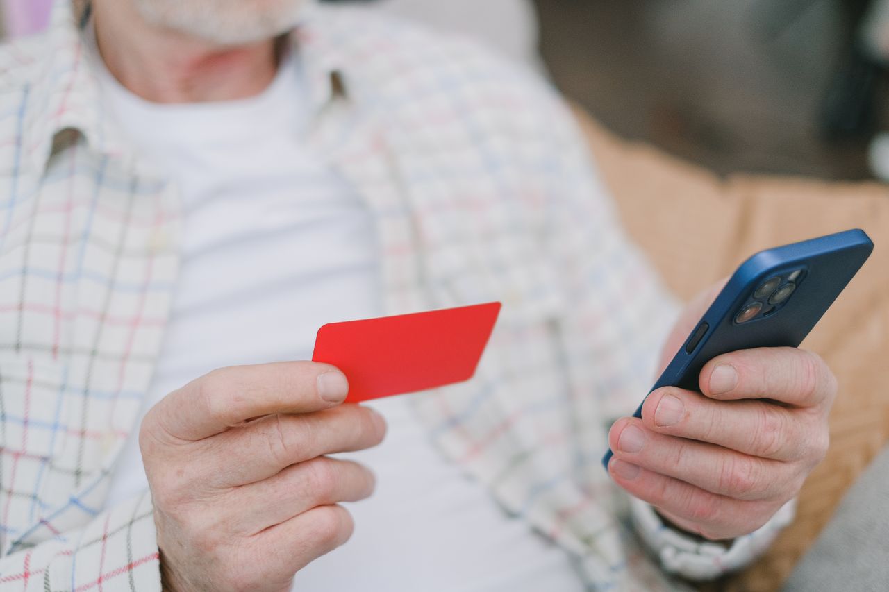 Hands holding a debit card and phone, as used for an Instant Transfer of Poshmark earnings