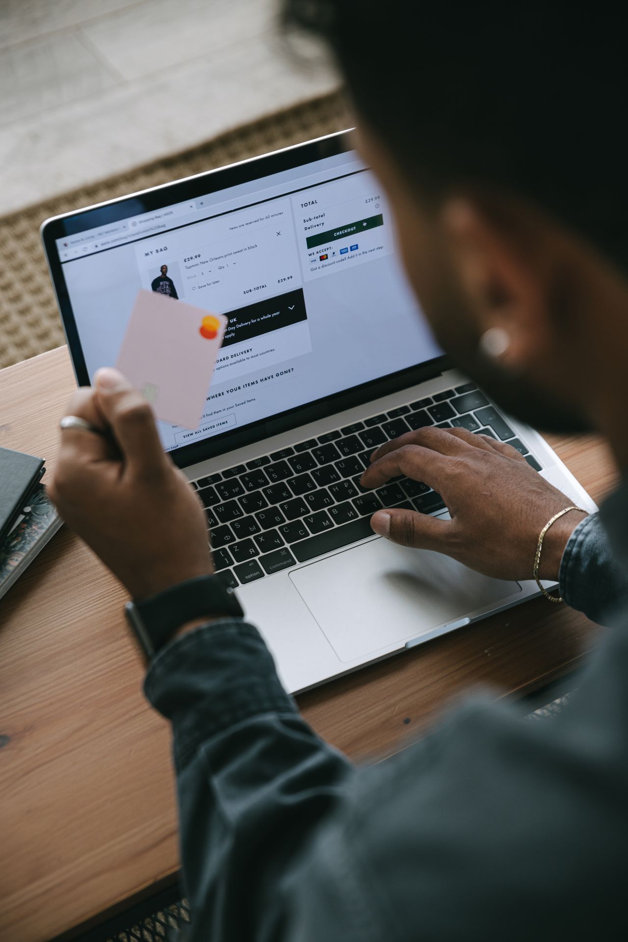 Man holding a card while paying online on his laptop, illustrating SamCart pricing and fees