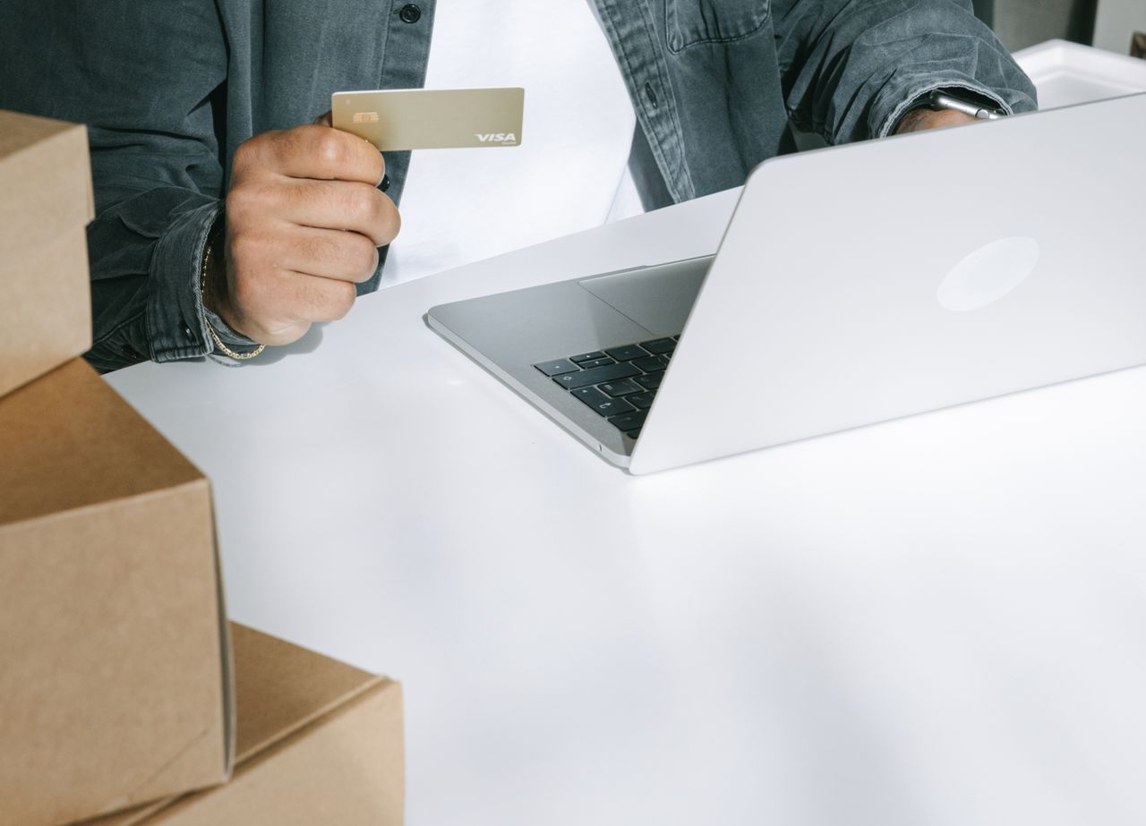 Shopper paying by card on a laptop among shipping boxes, the kind of store Sendlane email automation targets